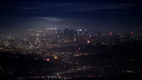 Epic shot of holiday celebration with multiple scenic fireworks rising above cityscape at night. Cinematic Los Angeles downtown view with people celebrating Independence day or New Year, USA