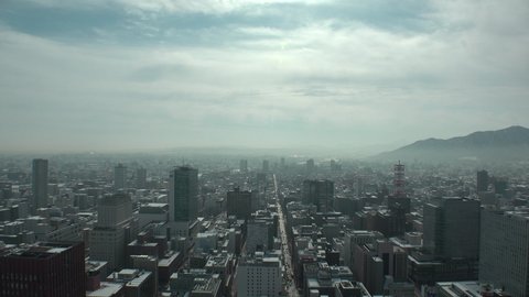 SAPPORO, HOKKAIDO, JAPAN - FEB 2020 : Aerial high angle view of cityscape of Sapporo city. View of buildings and street traffic around Susukino downtown area. Time lapse shot in day time.