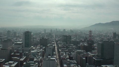 SAPPORO, HOKKAIDO, JAPAN - FEB 2020 : Aerial high angle view of cityscape of Sapporo city. View of buildings and street traffic around Susukino downtown area. Time lapse shot in day time.