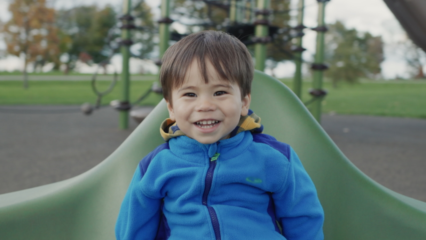 Carefree Asian kid rides on a merry-go-round, smiles and enjoys a walk.