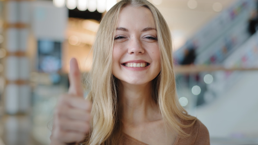 Close-up portrait of young smiling girl in mall happy satisfied woman showing thumb up looking at camera giving positive service or goods recommendation female client feeling satisfied approval symbol | Shutterstock HD Video #1083911098