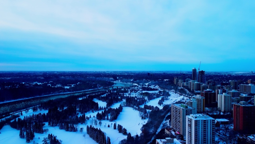 Winter aerial fly over the recreational park for cross country skiing skating and sledding from a repurposed summer use of golfing and team activities of baseball softball at the rivers of dt Edmonton