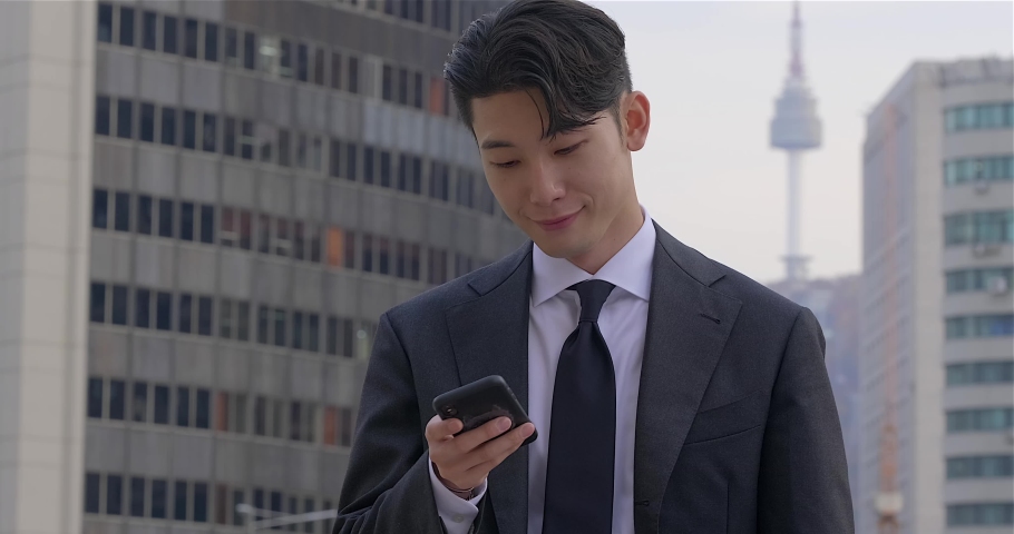Digital content on cellphone puts smile on face of young Asian businessman Royalty-Free Stock Footage #1083915706