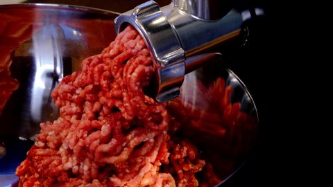 Minced meat cooking process. Household meat grinder side view. 4K footage with dark background