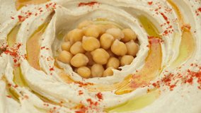 Hummus with smoked paprika, olive oil, whole chickpeas close up, rotation. Healthy vegan food. 4K UHD video