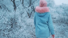 happy woman walks in winter park. Blue jeans jacket knitted pink hat stylish bright warm casual wear. Girl back view, turned away, no face. Background nature winter trees snow white hoarfrost cold day