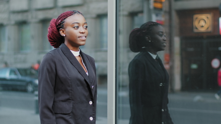 Young business woman african american girl lady walking near building of company office being late for interview meeting moves in street in city looking at wrist watch checking time walks moving going