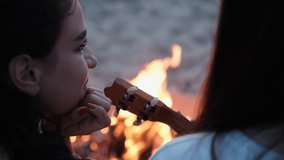 Young brunette girl plays by the fire on the slope. Girls are sitting on the beach by the fire. Summer holidays. Evening on the beach by the sea. Party of a young company. Friendly guys are resting on - Powered by Shutterstock - Get 15% off with code: PIKWIZARD15