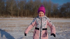 Cute girl dancing at winter and looking at camera outdoors. Female child dancer having fun outside. Positive face emotions. Leisure activity and happy childhood concept