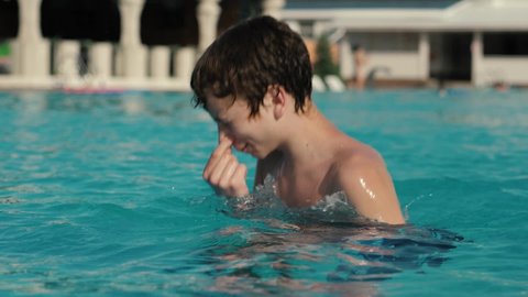 Teenager closes his nose and dives in the pool slow motion