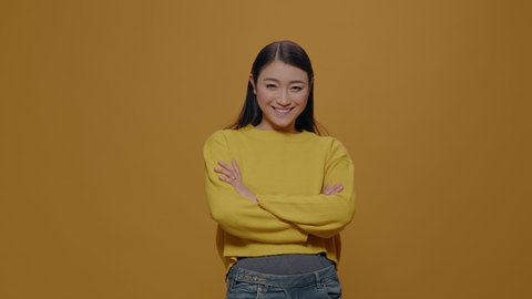 Portrait of asian woman standing with arms crossed over isolated background. Person feeling confident and looking at camera in studio, posing to show determination and confidence.