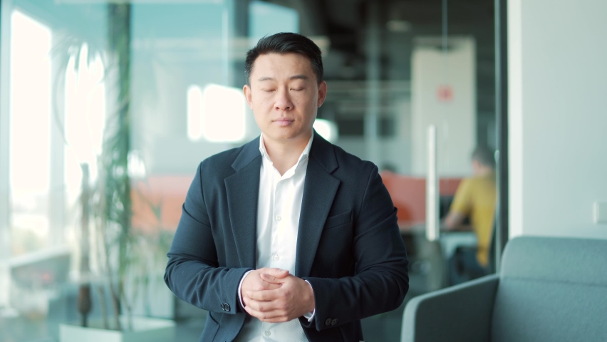 Asian business man speaker in formal suit talking looking at camera. Online meeting, conference or distance learning, remotely training via video call. Webcam view. standing in a modern office class Royalty-Free Stock Footage #1083929221