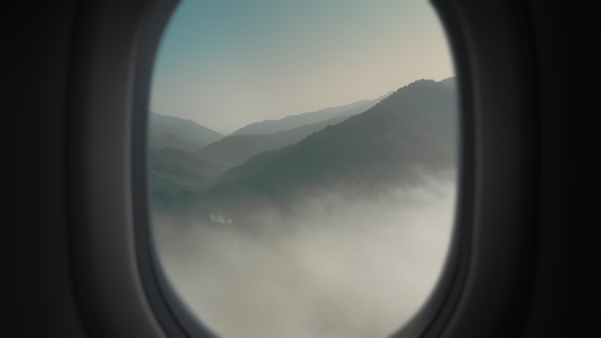 Aerial plane window landscape view Zoom out from mountains trough window in plane cabin | Shutterstock HD Video #1083929404