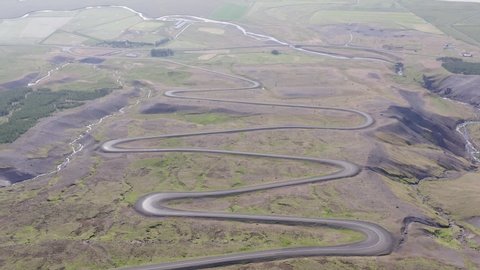 Winding dirt road with hairpin corners going up mountain side in Iceland, aerial