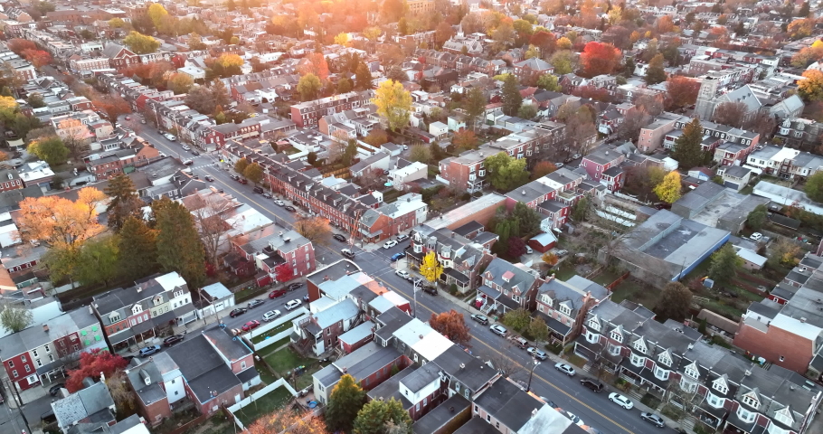 Cinematic high aerial establishing shot of American city. Town in suburbs during magic hour sunrise. Homes and houses line the streets in USA. Royalty-Free Stock Footage #1083930622