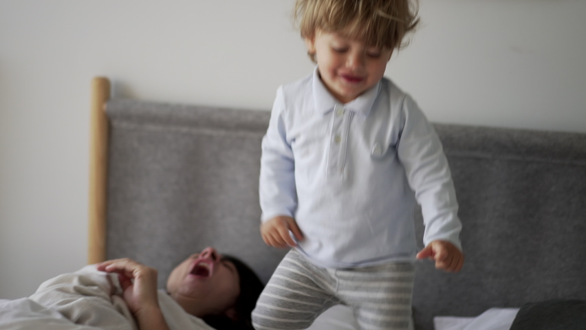 Baby toddler jumping up and down in bed. Child bouncing in the morning bed