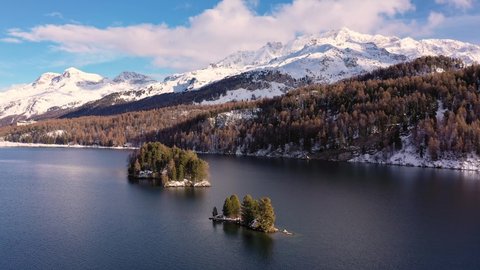 Aerial drone footage of the Silsersee lake in winter in the Engadine valley with the Corvatsch mountain peak in Canton Graubunden in the Swiss alps. Shot with a forward and rotation motion
