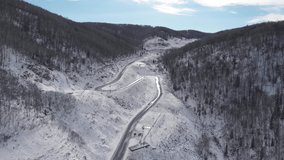Aerial 4k drone video of top view of winding winter road in the mountains, Altai Krai, Western Siberia, Russia. Road to Resort town Belokurikha 2