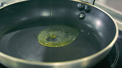 Close up of sunflower oil being poured on a hot frying pan. Boiling oil in a frying pan. Heated sunflower oil is ready for cooking.