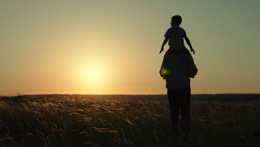 Child and dad play together and travel through the park in spring at sunset. Happy family. Silhouette, the son sits on the shoulders of the father. Dad little child walk on the grass outdoors Royalty-Free Stock Footage #1083938101