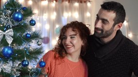 Couple enjoying decorating Christmas tree in living room. Holidays preparation. - Powered by Shutterstock - Get 15% off with code: PIKWIZARD15