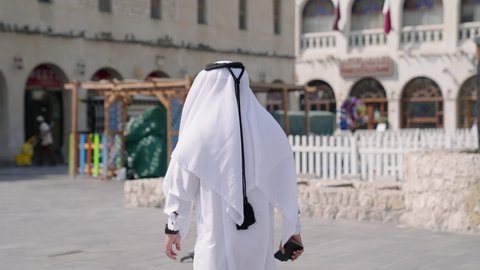 Qatari man walking in front Souq Waqif in Doha Qatar
