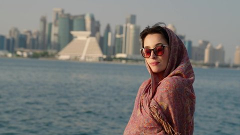 Muslim beautiful girl in traditional Abaya dress with Doha skyline behind
