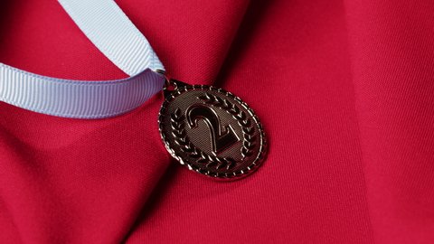 Silver medal with ribbon on red background close-up. The second place. Award and victory, winning the championship. 