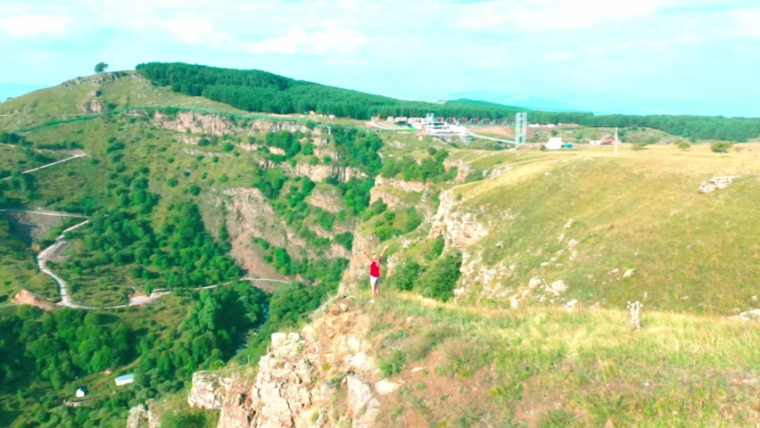 A girl in red clothes stands on the verge of the mountain