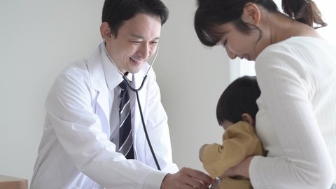 Asian doctor palpating a baby