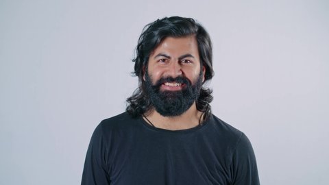 A young modern Indian Asian attractive bearded man with a wide smile on his face looking towards camera isolated on white background.