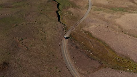 Aerial view off road 4x4 car driving along gravel trail path. Drone view on offroad vehicle on desert road travelling in Iceland. Commercial and insurance. Freedom and wanderlust
