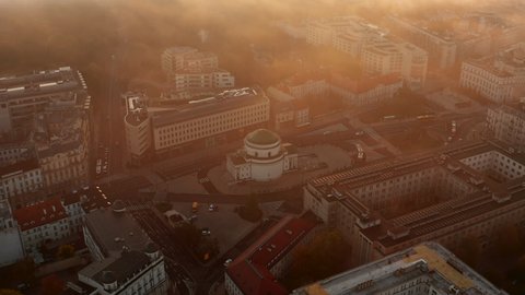 Aerial shot of church at Three Crosses Square. Golden morning sun glowing into mist. Fly above town. Warsaw, Poland