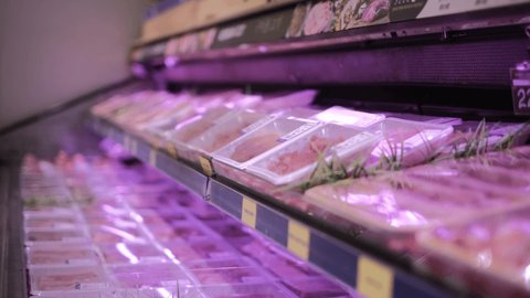 Many packaged raw meat on the supermarket shelves, assortment on showcase in a butcher shop