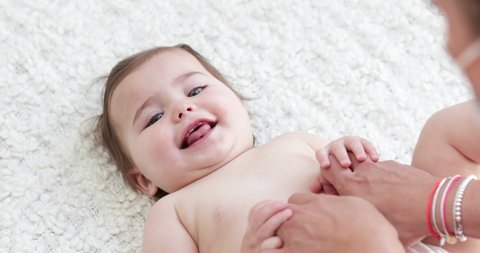 baby girl lying on her back with diapers enjoying tickling game slow motion