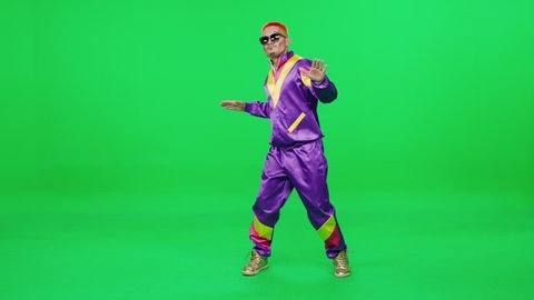 Belarus, Minsk - September 13, 2021: Pretentious retro guy in a purple suit dancing to the music on a green background, young digital influencer creates content, chromakey template.