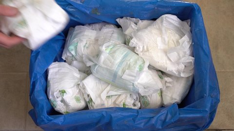 Wet and dirty disposable diapers. Mother throws the used diaper in the trash can