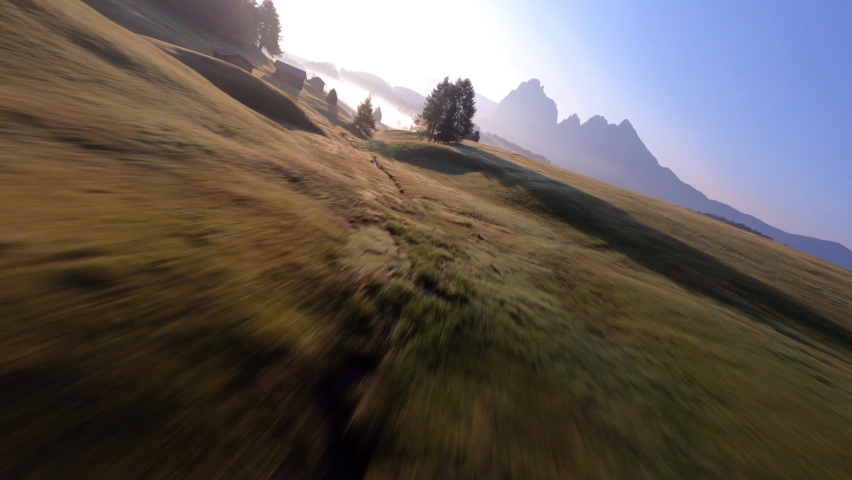 FPV drone flying above the trees at Alpi di Siusi, Seiser Alm. Dolomiti mountains, South Tirol, Dolomiten mountains view, Italian Alps. Clouds moving fast
