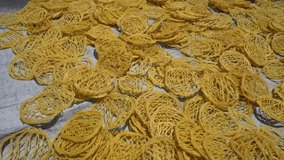 Raw yellow crackers being dried on a plastic mat. 