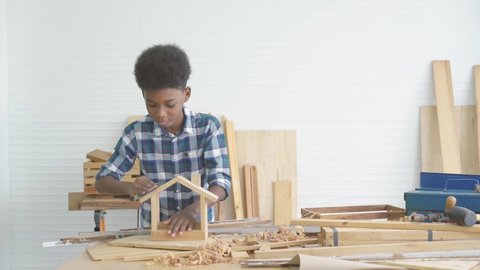 Smiling african american kid carpenter happy working with wood and sandpaper, Boy happy working with wood handyman creating frame comfort zone, Education, preschool and learning concept.
