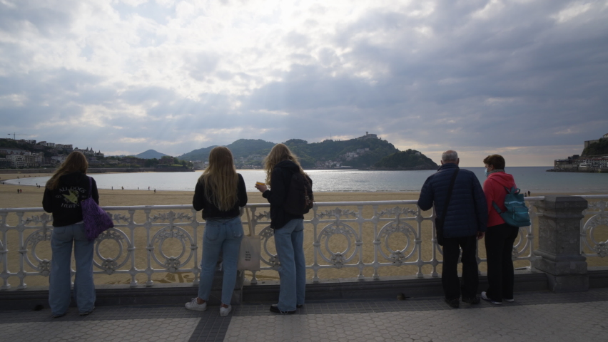 People admire majestic view of San Sebastian bay while on coastal pathway, gimbal motion