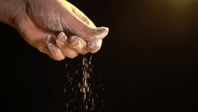 male hand throws flour on a black background. cooking baking concept. blurred video. film grain