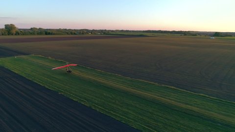 Motorized hang glider lands on the grass runway