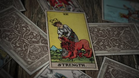 Zurich, Switzerland – November 25, 2021: Esoteric Magic Reading Of The Strength Tarot Card. Esoteric Magic Card During Occult Cartomancy Prediction. Esoteric Magic Card Deck Shuffling. Paranormal