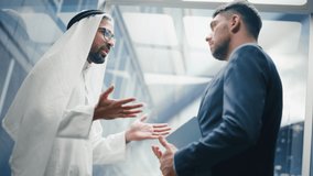 Businessman Talking with Arab Investment Partner while Riding Glass Elevator to Office in a Modern Business Center. International Corporate Associates Shake Hands and Agree on a Deal in a Lift. - Powered by Shutterstock - Get 15% off with code: PIKWIZARD15