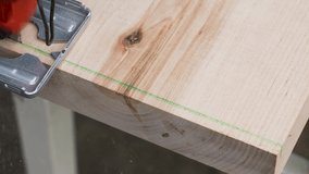 Close-up view 4k stock video footage of man cutting wooden boards using electric saw tool
