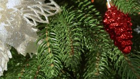 Close-up view 4k stock video footage of beautiful green Christmas tree decorated with bright holiday ornaments and led light garlands glowing on needles. Abstract holiday Xmas background