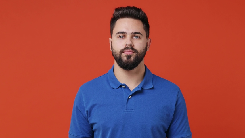 Young bearded brunet man 20s wears blue t-shirt dance waving rising expressive gesticulating hands fool around snaps his fingers to music rhythm isolated on plain red orange background studio portrait Royalty-Free Stock Footage #1083978004