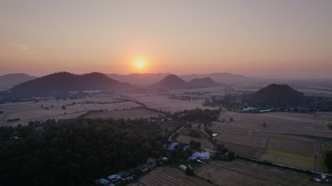 Aerial view of Colorful sunset over mountain and harvested paddy fields in farmland at countryside