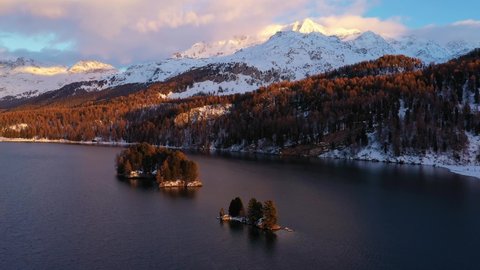 Aerial drone footage of the Silsersee lake in winter in the Engadine valley with the Corvatsch mountain peak in Canton Graubunden in the Swiss alps. Shot with a forward and rotation motion